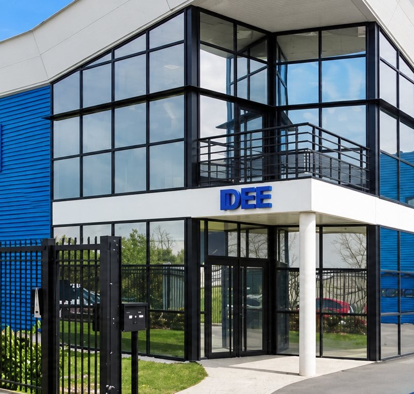 Entrée vitrée du bâtiment IDEE sous l'enseigne bleue, avec son portail noir.